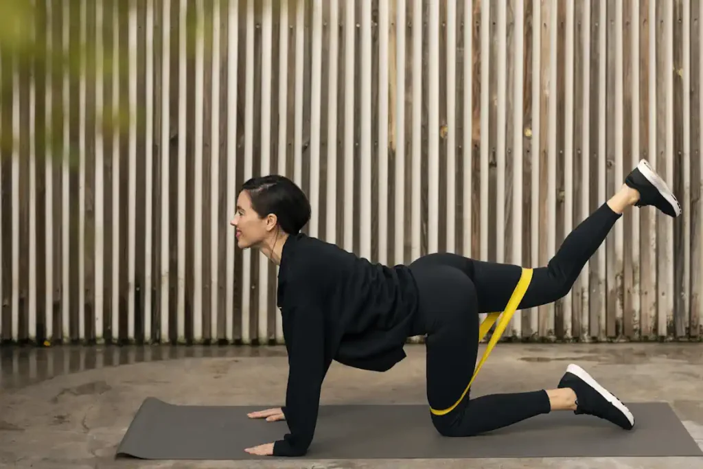 Une femme qui fait des exercices de fessiers sur le sol avec un élastique autour des jambes
