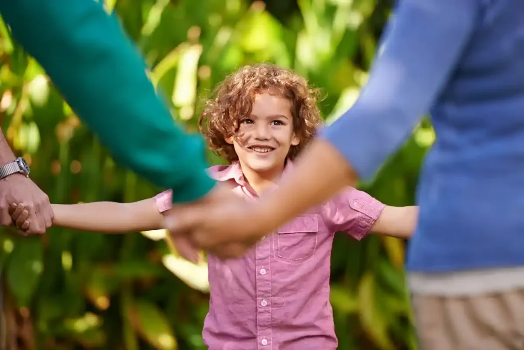 Un petit garçon souriant qui tient la main de ses parents