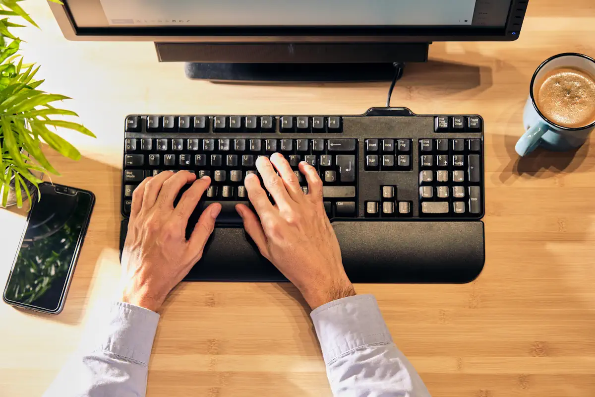 Une personne qui travaille sur son clavier d'ordinateur avec un repose-poignet