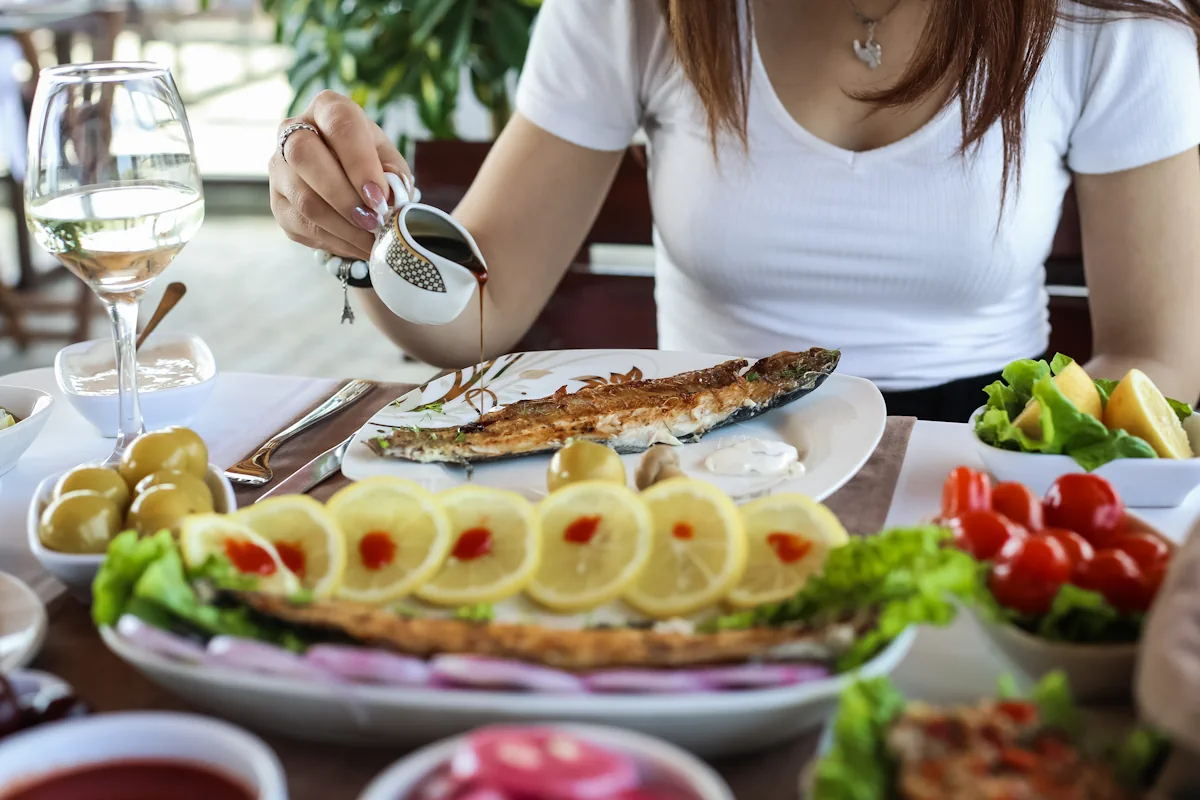 Une femme devant une assiette de poisson et des citrons coupés en rondelles