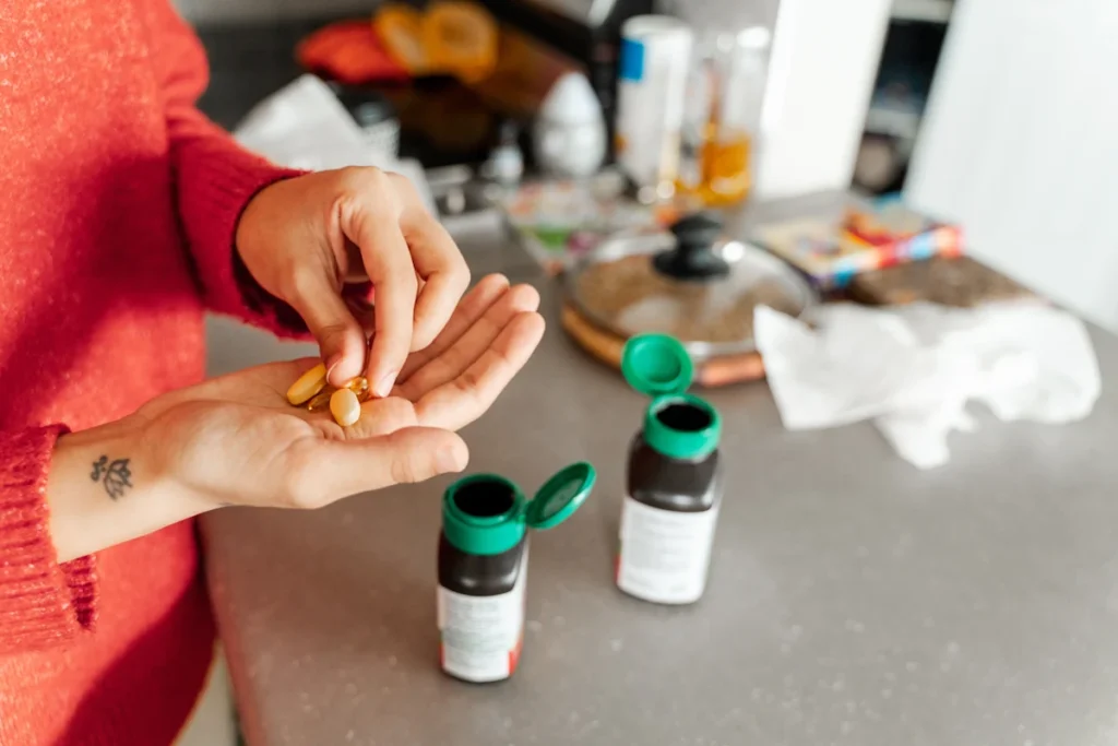 Une femme qui regarde des gélules qu'elle a mis dans sa main