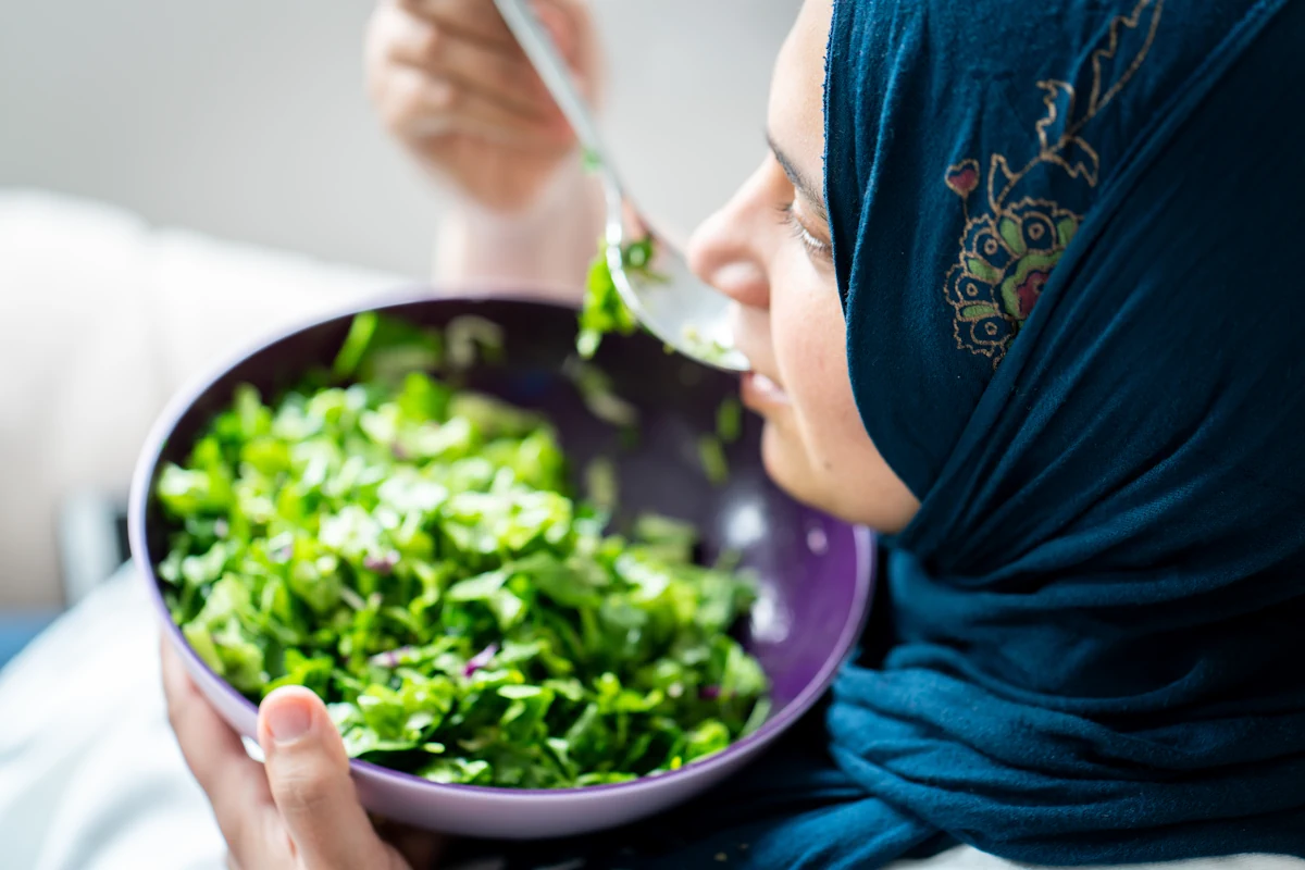 Une femme qui mange un bol d'épinards