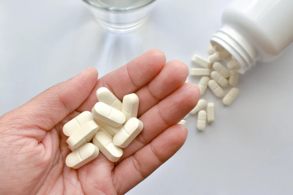 Une personne qui tient des gélules blanches dans sa main
