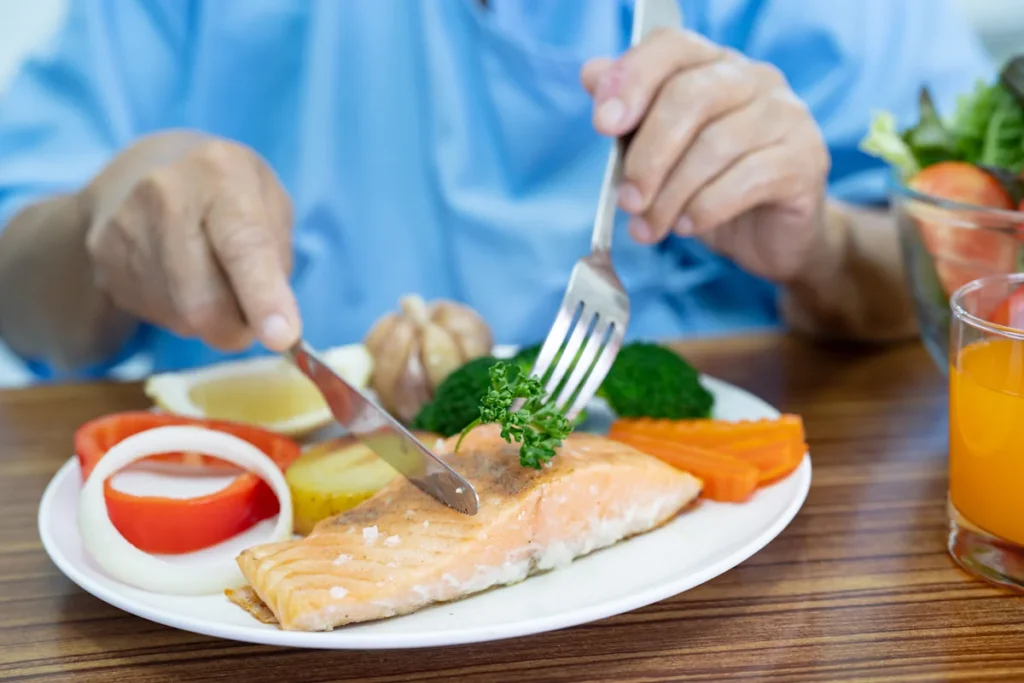 Une personne qui mange un poisson et des légumes dans son assiette