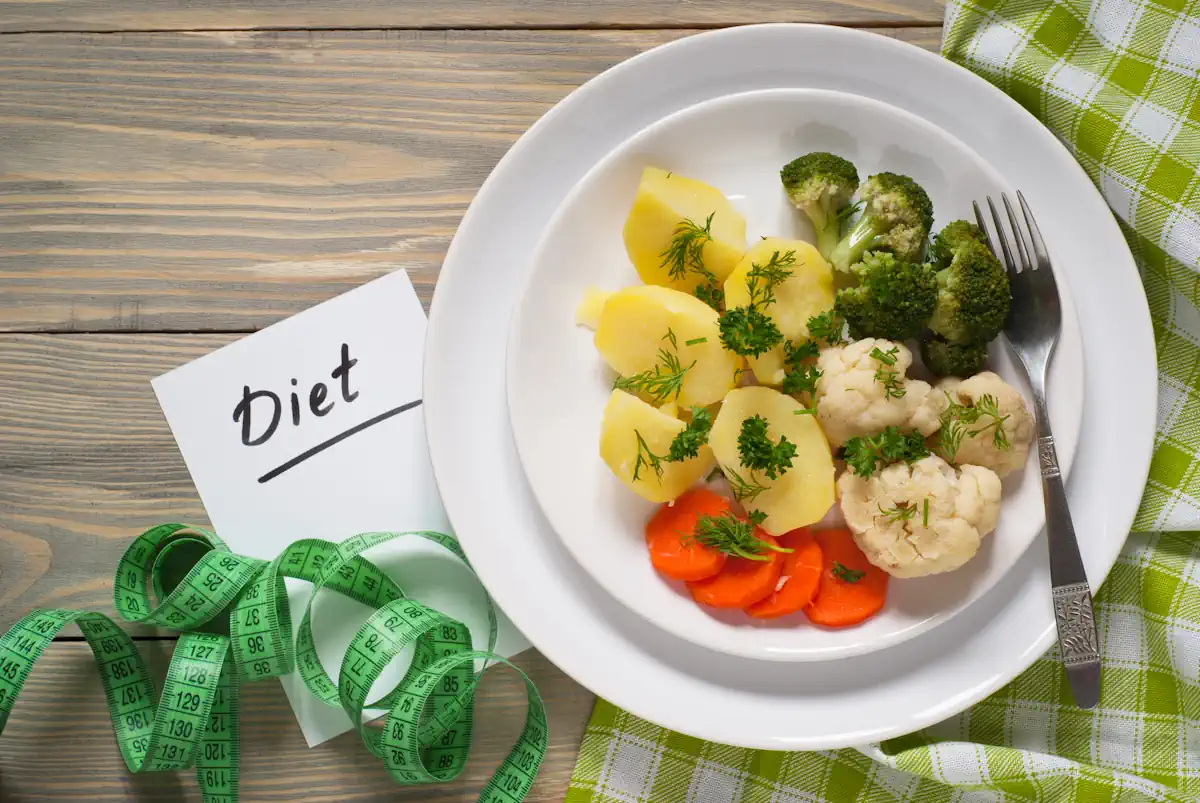 Une assiette de légumes posé à côté d'un mètre ruban avec le mot Diet sur un papier