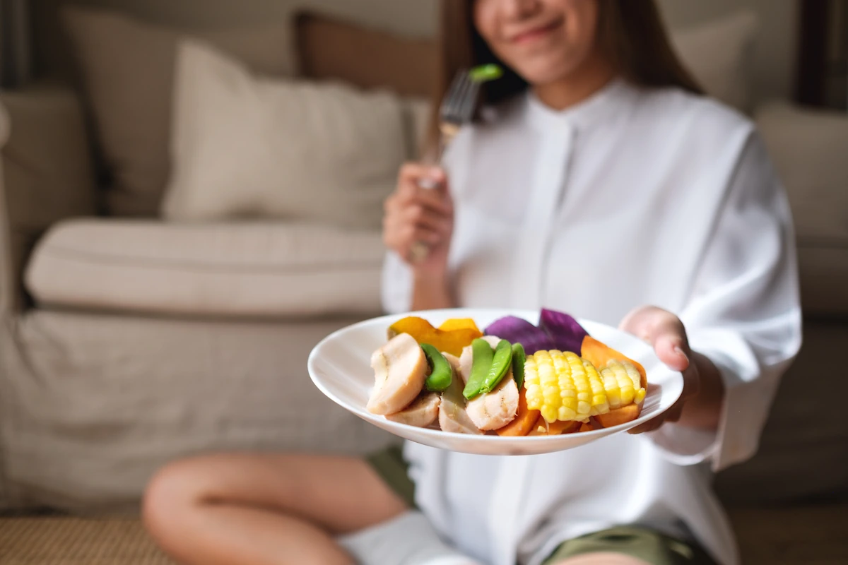 Une femme qui présente une assiette de viande blanche et de légumes