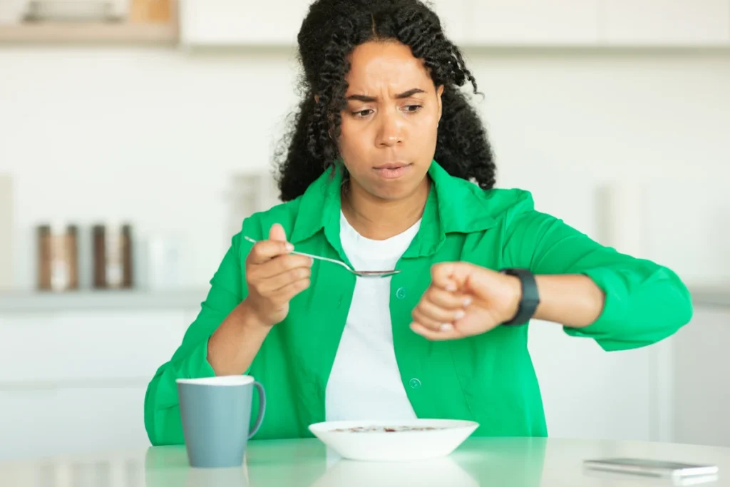 Une femme qui mange en regardant sa montre