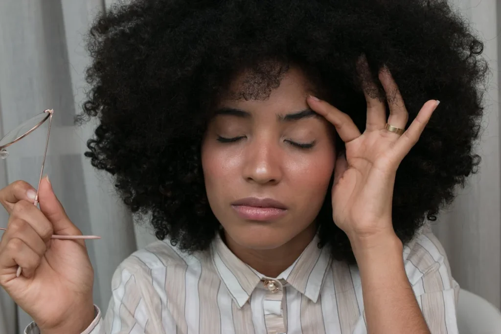 Une femme qui ferme les yeux en tenant sa tête