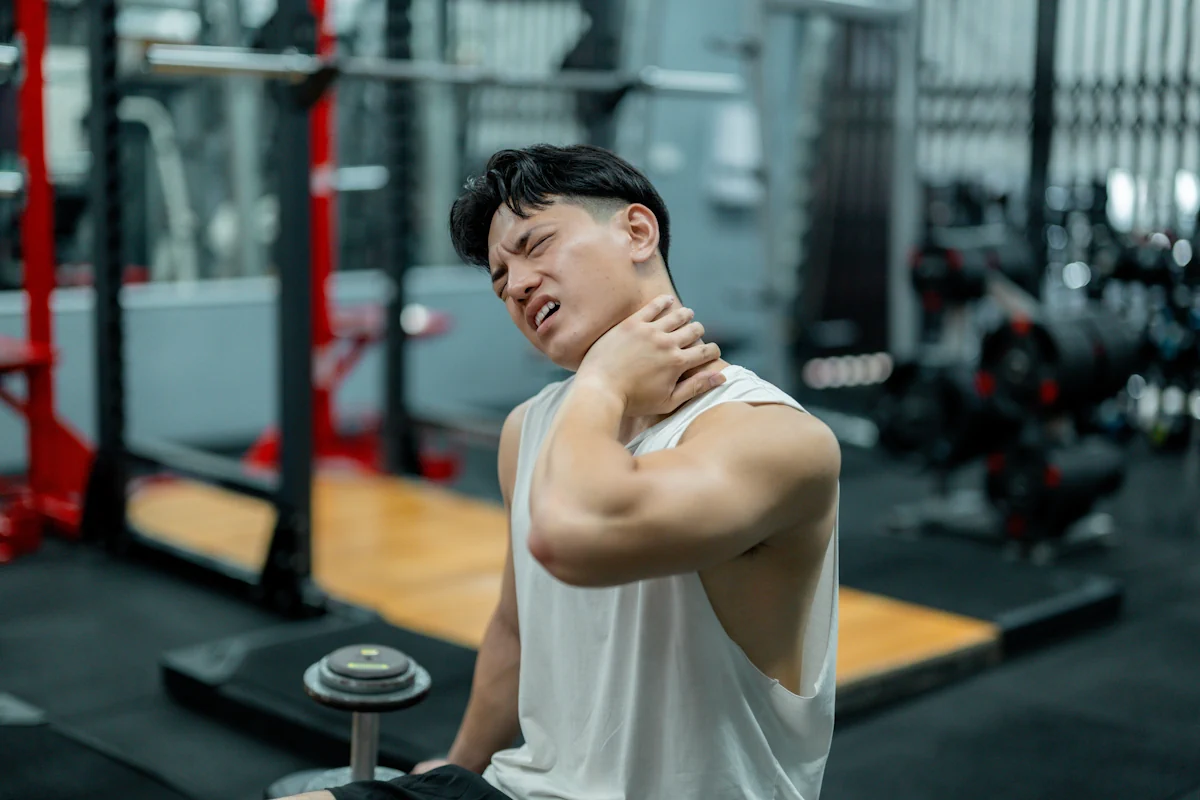 Un homme qui se tient la nuque dans une salle de sport