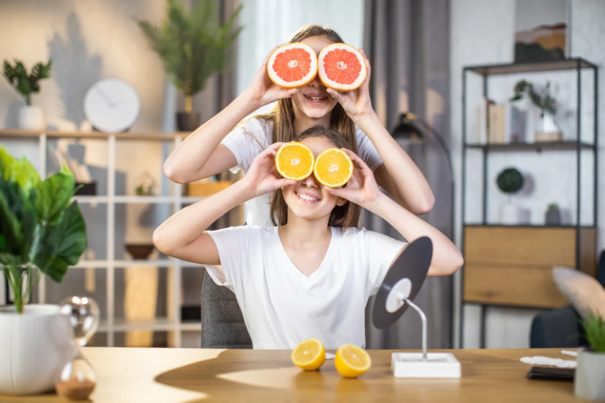 Deux jeunes filles qui mettent des oranges su rles yeux