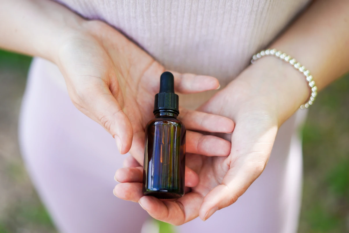 Une personne qui tient un flacon d'huile essentielle dans ses mains