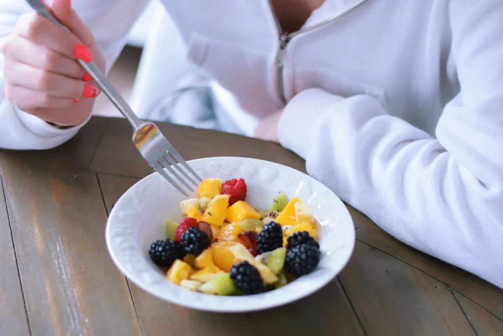 Une personne qui mange une assiette de fruits