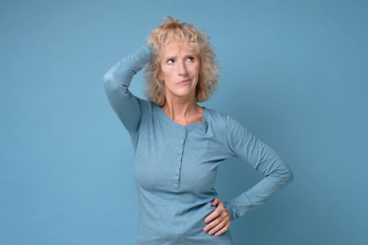 Une femme en tenue bleue qui se frotte la tête