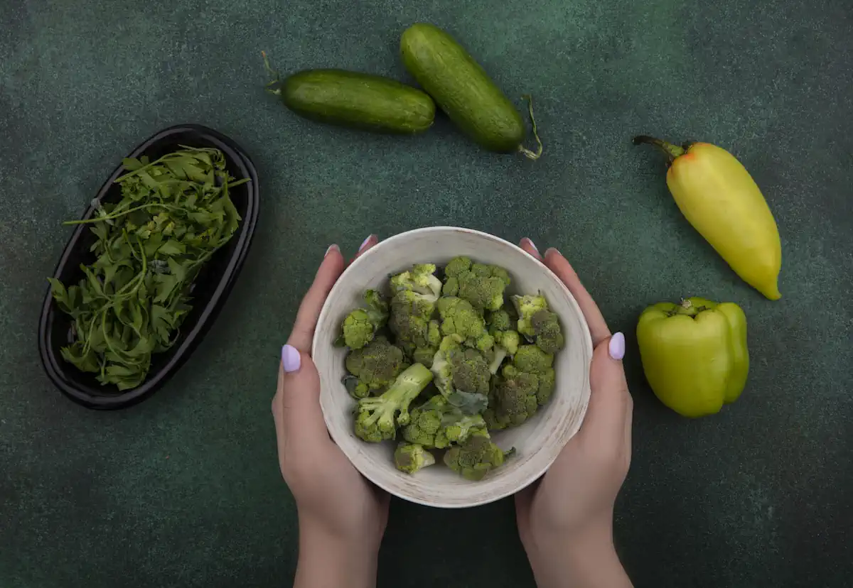 Une personne qui tient un bol avec des légumes verts