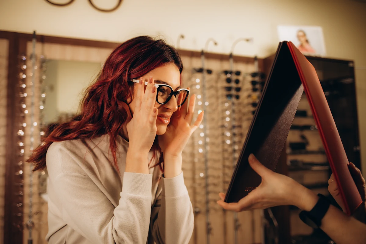 Une femme qui essaie des lunettes en se regardant dans un miroir