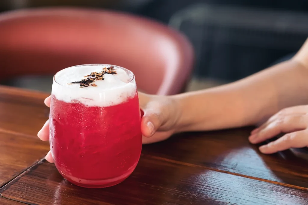 Une personne qui tient un verre de jus de cranberry