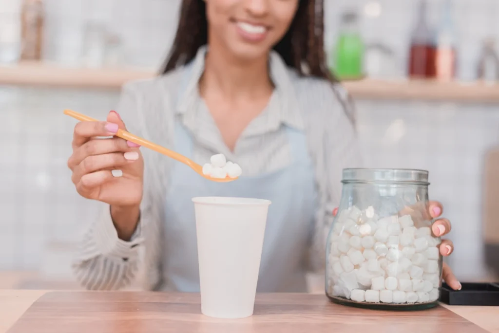 Une femme qui ajoute du sucre dans sa boisson
