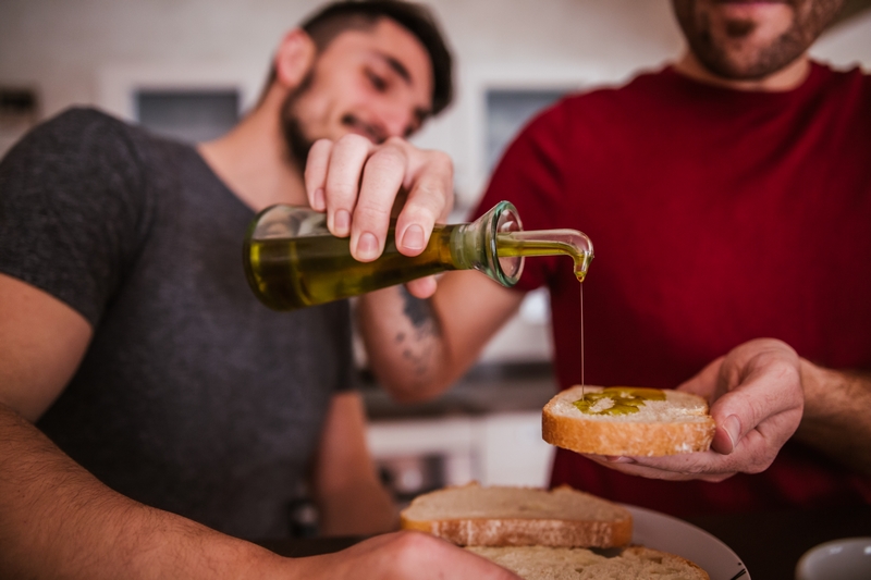 hommes qui se préparent des tartines avec de l'huile d'olive