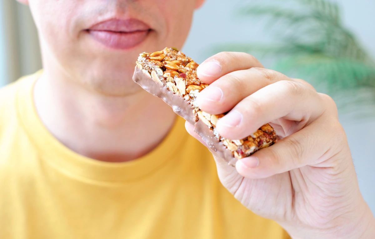 un homme en période de sèche sportive qui mange des barre céréalière "sport"