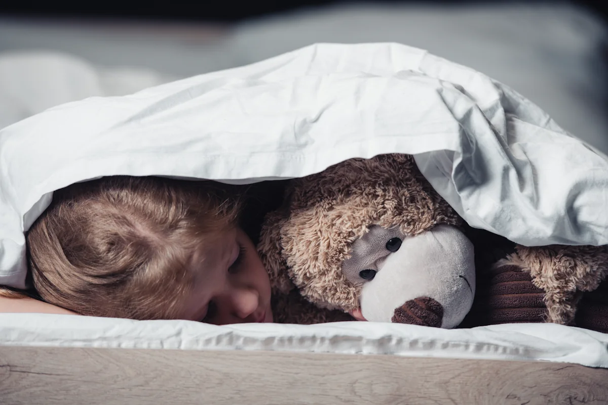 Un enfant qui dort profondément avec son ourson en peluche