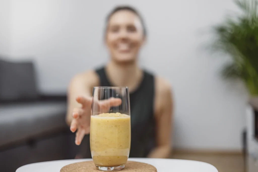 Une femme qui prend un verre de Smoothie prise de masse maison