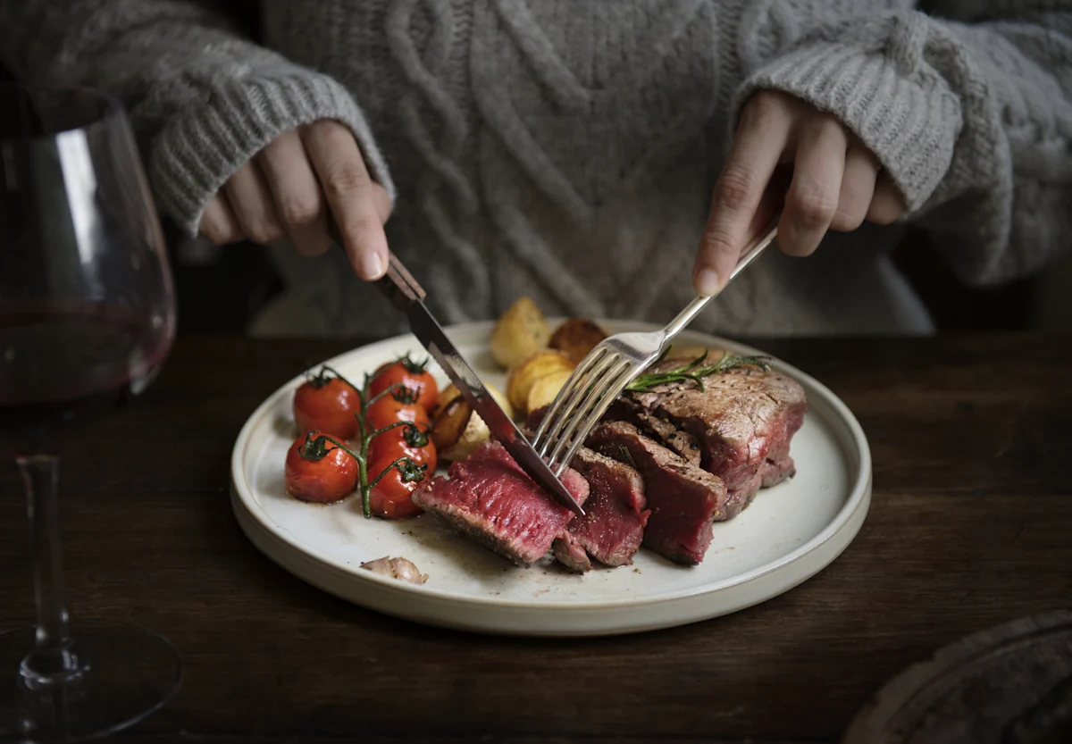 Une personne qui mange de la viande rouge pour un meilleur apport en zinc