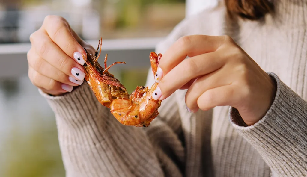 Une personne qui mange du crevette pour un meilleur apport en zinc