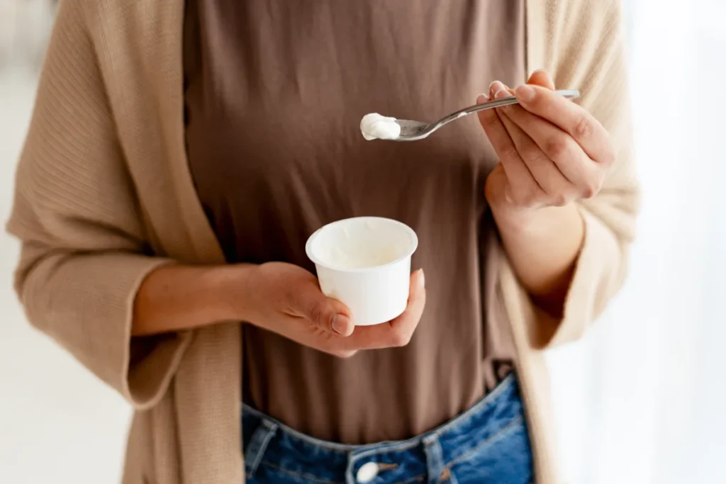 Une femme qui mange un yaourt pour un meilleur apport en calcium
