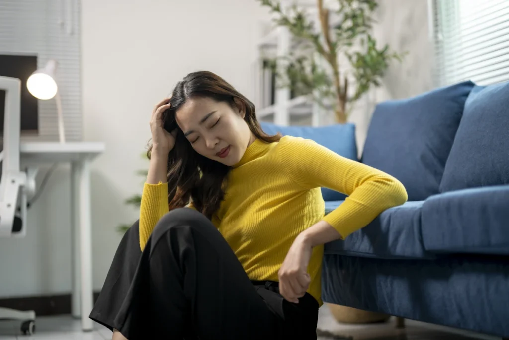 Une femme fatiguée assise au sol contre le canapé