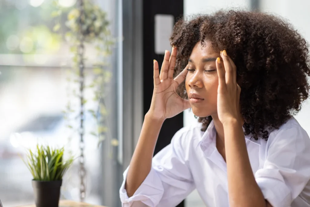 Une femme stressée qui ferme les yeux en se tenant la tête