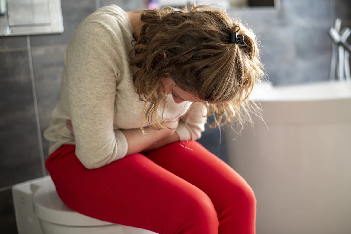 Une femme assise aux toilettes avec une constipation par manque de potassium