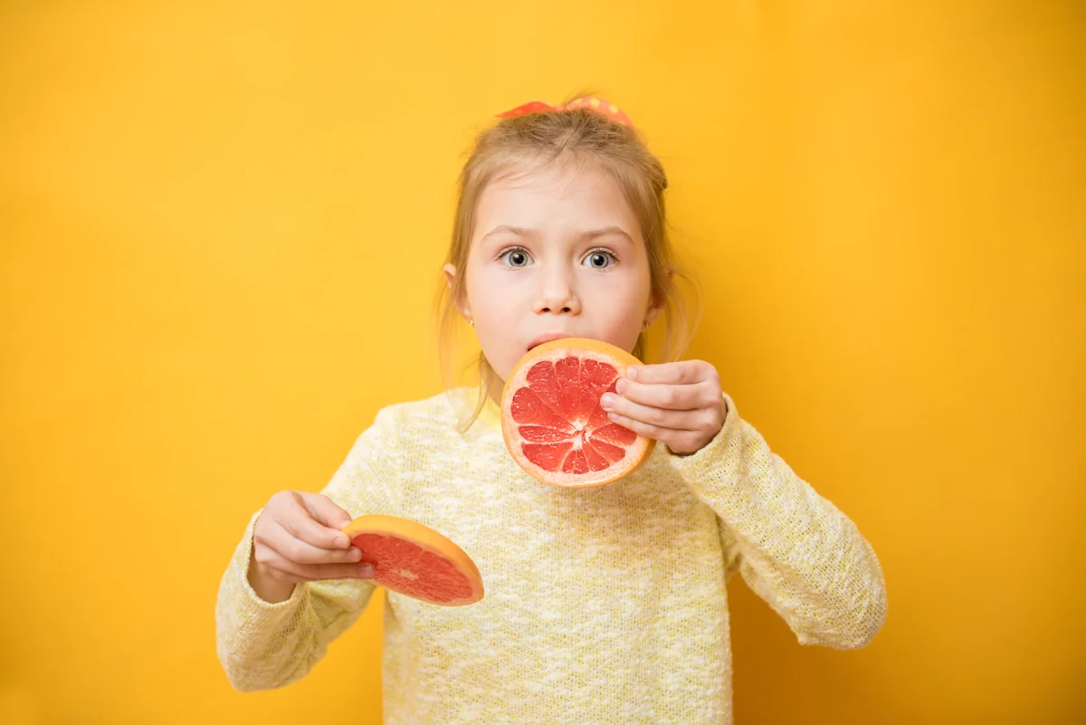 Une petite fille qui mange du pamplemousse