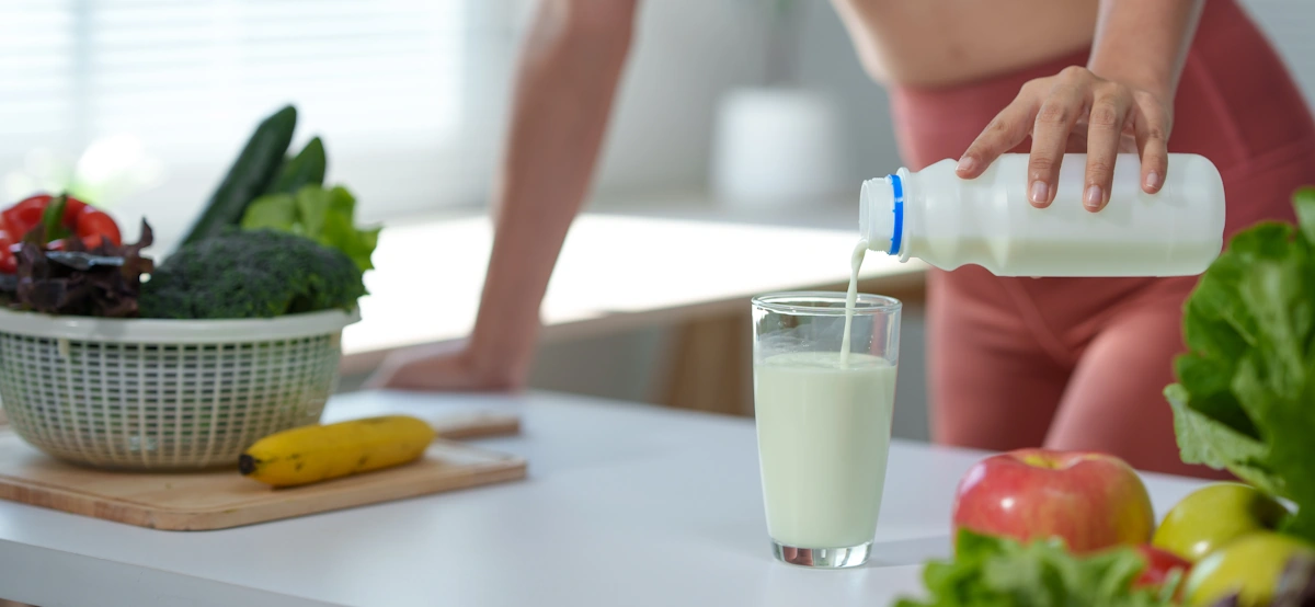 Une femme qui verse un kéfir de lait dans un verre